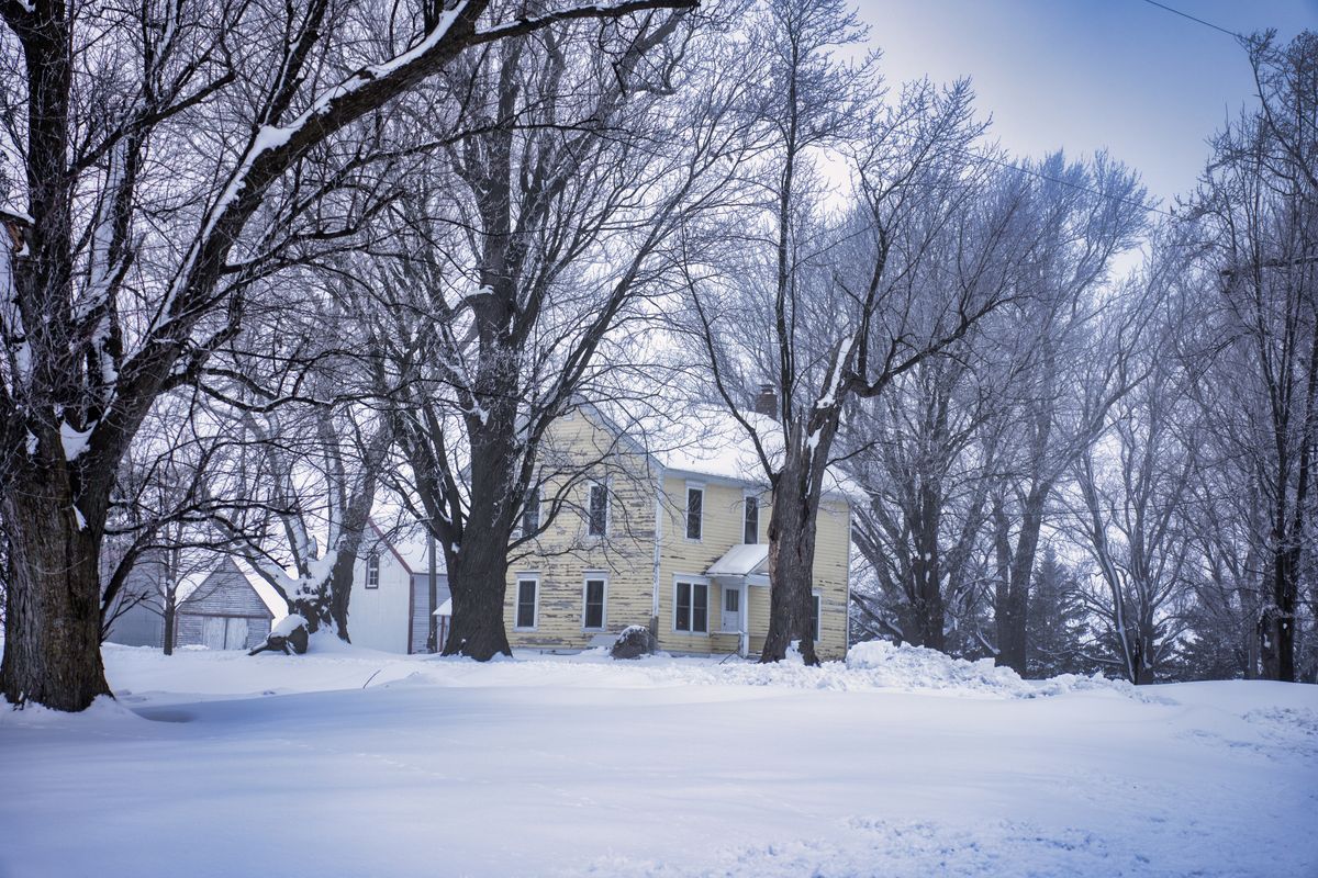 Rural Minnesota farmhouse surrounded by snow and frosted trees in deep winter